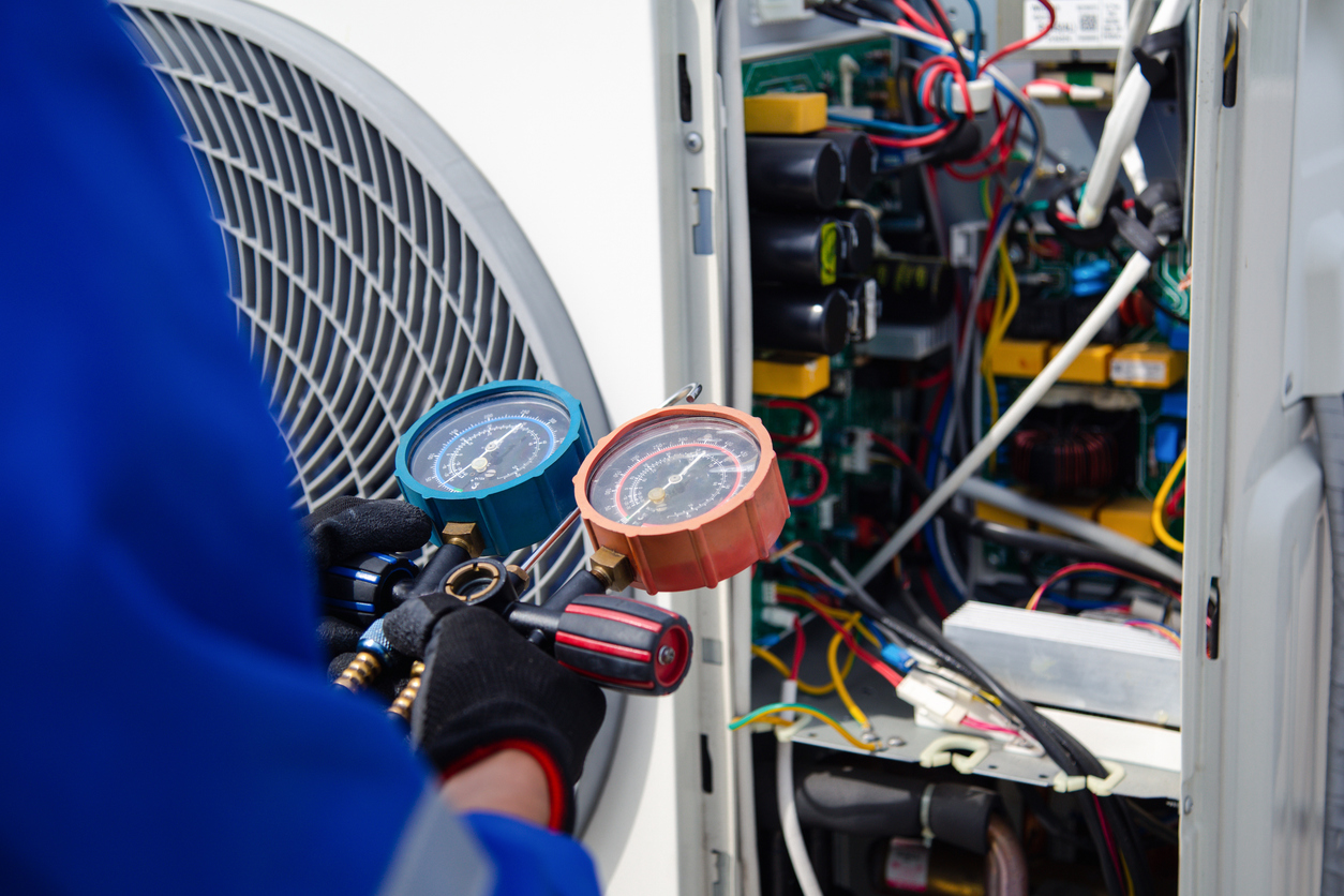 The air conditioner technician is using a gauge to measure the refrigerant pressure. air compressor.
